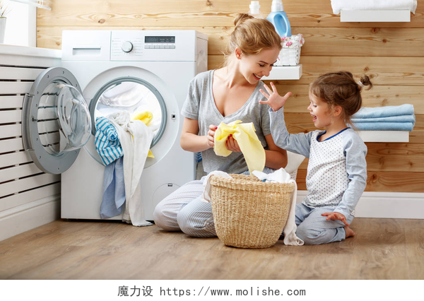 快乐家庭主妇和孩子母女在用洗衣机洗衣快乐家庭母亲的家庭主妇和孩子在洗衣店与塑封